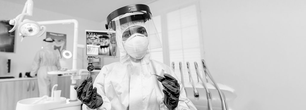 dentist gearing up in all the required ppe to operate